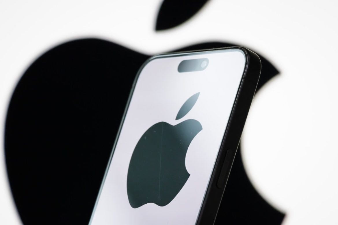 In this photo illustration, the logo of Apple Inc. is displayed on a smartphone screen, with the company's iconic black apple symbol visible in the background.